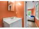 Bathroom features an orange wall and a white vanity with cabinets, and is adjacent to bedroom at 1513 Dellwood Dr, Raleigh, NC 27607