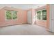 Bright bedroom featuring two windows, light peach walls, and plush carpeting at 1601 Castalia Dr, Cary, NC 27513