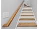 Staircase with natural wood treads, white risers, and a wooden handrail with modern wall switches at 1723 Kudrow Ln, Morrisville, NC 27560