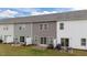 View of townhome backyards with sliding glass doors, patios, and green lawns at 19 Willow Green Dr, Clayton, NC 27527