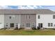 Backyard view of 3 townhomes, showcasing grass, patios, and sliding glass doors for indoor/outdoor living at 19 Willow Green Dr, Clayton, NC 27527