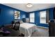 Comfortable bedroom featuring blue walls, a gray bed, a ceiling fan, and a study space at 2003 Pilot Mountain Ct, Apex, NC 27502