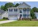 Charming two-story home with a covered front porch, an American flag, a two-car garage, and a well-manicured lawn at 2003 Pilot Mountain Ct, Apex, NC 27502