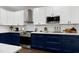 Modern kitchen featuring navy base cabinets, white upper cabinets, and stainless steel appliances at 2003 Pilot Mountain Ct, Apex, NC 27502