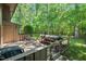 Large backyard featuring patio space with seating, a grill, mature trees, and a serene view at 202 Oak Tree Dr, Chapel Hill, NC 27517