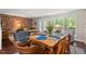 Cozy dining room featuring a wooden table set for four with a brick accent wall, hardwood floors, and a large window at 202 Oak Tree Dr, Chapel Hill, NC 27517