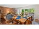 Cozy dining room featuring a wooden table set for four with a brick accent wall, hardwood floors, and a large window at 202 Oak Tree Dr, Chapel Hill, NC 27517