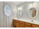Bathroom showcasing double sinks with a wood vanity, oval mirrors, and an ornate oval window at 2030 Prairie Ridge Ct, Fuquay Varina, NC 27526