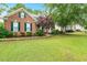 Attractive brick home featuring a green lawn, mature trees, and well-maintained landscaping at 2030 Prairie Ridge Ct, Fuquay Varina, NC 27526