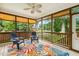 Charming screened-in porch with colorful rug, ceiling fan, and wooded views at 2030 Prairie Ridge Ct, Fuquay Varina, NC 27526
