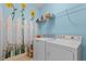 Bright laundry room with whimsical sunflower mural and modern washer and dryer at 2503 Saint Pauls Sq, Raleigh, NC 27614