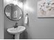 Powder room featuring pedestal sink, round mirror, and gray walls at 303 Middleham Dr, Rolesville, NC 27571