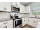 Close up of kitchen with stainless steel appliances, granite countertops, white subway tile backsplash, and white cabinets at 307 W Copenhaver Dr, Clayton, NC 27527
