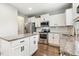 Well-lit kitchen features stainless steel appliances, an island, granite countertops, subway tile backsplash, and hardwood floors at 307 W Copenhaver Dr, Clayton, NC 27527