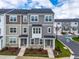 Modern townhome showcasing multiple gray tones, a covered entryway and manicured lawn with beautiful landscaping at 3101 Brellon Ln, Durham, NC 27703