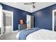 A bedroom boasts blue walls, a ceiling fan, and easy access to a bathroom and staircase at 320 Chickasaw Plum Dr, Holly Springs, NC 27540