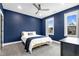 A modern bedroom painted with blue walls features a ceiling fan and plush queen-sized bed near bright windows at 320 Chickasaw Plum Dr, Holly Springs, NC 27540