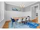 Chic dining room featuring hardwood floors, large windows, and a modern chandelier creating a warm and inviting atmosphere at 320 Chickasaw Plum Dr, Holly Springs, NC 27540
