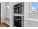 Built-in stainless steel oven and microwave with white cabinetry, and butcher block bench at 320 Chickasaw Plum Dr, Holly Springs, NC 27540