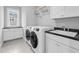 Modern laundry room featuring sleek cabinetry, granite countertops, and brand-new washer and dryer at 320 Chickasaw Plum Dr, Holly Springs, NC 27540