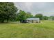 Back of home featuring a spacious green yard, blue metal roof, and access to a backyard deck at 403 Rolling Rd, Haw River, NC 27258