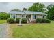 Charming home features a bright blue metal roof, manicured landscaping, and paved front walkway at 403 Rolling Rd, Haw River, NC 27258
