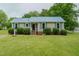 Charming home features a bright blue metal roof, manicured landscaping, and covered front entry at 403 Rolling Rd, Haw River, NC 27258