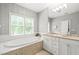 Bathroom featuring double sink vanity, soaking tub with tile surround, and large window at 404 S Camellia St, Chapel Hill, NC 27516
