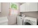 Bright laundry room featuring a washer, dryer, and ample storage cabinets under a window at 404 S Camellia St, Chapel Hill, NC 27516