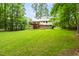 Lush backyard view with a two-story house featuring a wooden deck, surrounded by mature trees at 5001 Simpson Dr, Sanford, NC 27330
