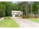 Split level home with beige siding, brick accents, metal roof, driveway, and mature landscaping at 5001 Simpson Dr, Sanford, NC 27330