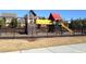 Community playground with swings, a slide, climbing wall, and other play structures in a fenced yard at 5016 Trembath Ln, Cary, NC 27519