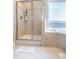 Bright bathroom with tiled shower, soaking tub, and light neutral tile throughout the room at 5016 Trembath Ln, Cary, NC 27519