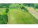 Expansive aerial view showcases the property's rolling green fields, pond, and mature trees with other farm buildings at 623 Chambers Rd, Rougemont, NC 27572