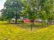 Fenced backyard featuring mature trees and partial view of a red home with a metal roof at 623 Chambers Rd, Rougemont, NC 27572