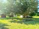 Landscaped backyard featuring mature shade trees, outbuildings and picnic tables at 623 Chambers Rd, Rougemont, NC 27572