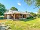 Exterior view of a brick home featuring a metal roof, patio, and satellite dish in a large grassy yard at 623 Chambers Rd, Rougemont, NC 27572