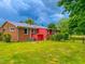 Exterior side view of a red home with a metal roof and brick accents in a large yard at 623 Chambers Rd, Rougemont, NC 27572