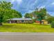 Charming brick home featuring a lush green lawn, beautiful trees, and outbuildings on a picturesque property at 623 Chambers Rd, Rougemont, NC 27572