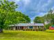 Charming brick home with a metal roof, a lush lawn, mature trees, and a covered entry at 623 Chambers Rd, Rougemont, NC 27572