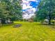 A picnic table sits on the expansive lawn in front of the red barn, framed by mature trees at 623 Chambers Rd, Rougemont, NC 27572