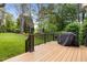 Backyard deck with black railings, grill, and a view of the green grass with well placed trees at 6648 Mafolie Ct, Raleigh, NC 27613