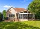 View of a well-maintained backyard with a deck, three-season porch, and lush green lawn at 6648 Mafolie Ct, Raleigh, NC 27613
