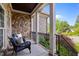 Charming porch with stone and brick walls, supported by columns, with comfortable wicker chairs for relaxing at 6648 Mafolie Ct, Raleigh, NC 27613