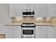 Close up of a kitchen with granite countertops, a stainless steel oven and range hood and white cabinets at 804 Harsworth Dr, Cary, NC 27519