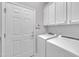 Laundry room featuring white cabinets, modern washer and dryer, and a door at 804 Harsworth Dr, Cary, NC 27519