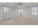 A bright main bedroom with tray ceiling, ceiling fan and three large windows at 986 Gateway Commons Cir, Wake Forest, NC 27587