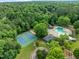 An aerial view of neighborhood tennis courts, a pool, a clubhouse, a sand volleyball court, and lush trees at 1013 New Chester Ct, Apex, NC 27502
