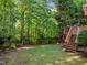 Beautiful backyard with lush trees and landscaping, plus a wooden deck accessible via stairs at 1013 New Chester Ct, Apex, NC 27502