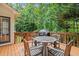 Outdoor deck with table, chairs, grill, and surrounded by lush greenery and trees at 1013 New Chester Ct, Apex, NC 27502